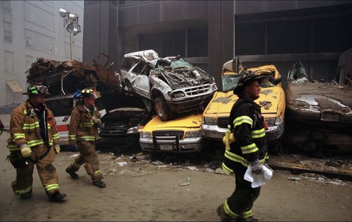 Firefighters passing a pile of damaged vehicles near Ground Zero on September 14, 2001