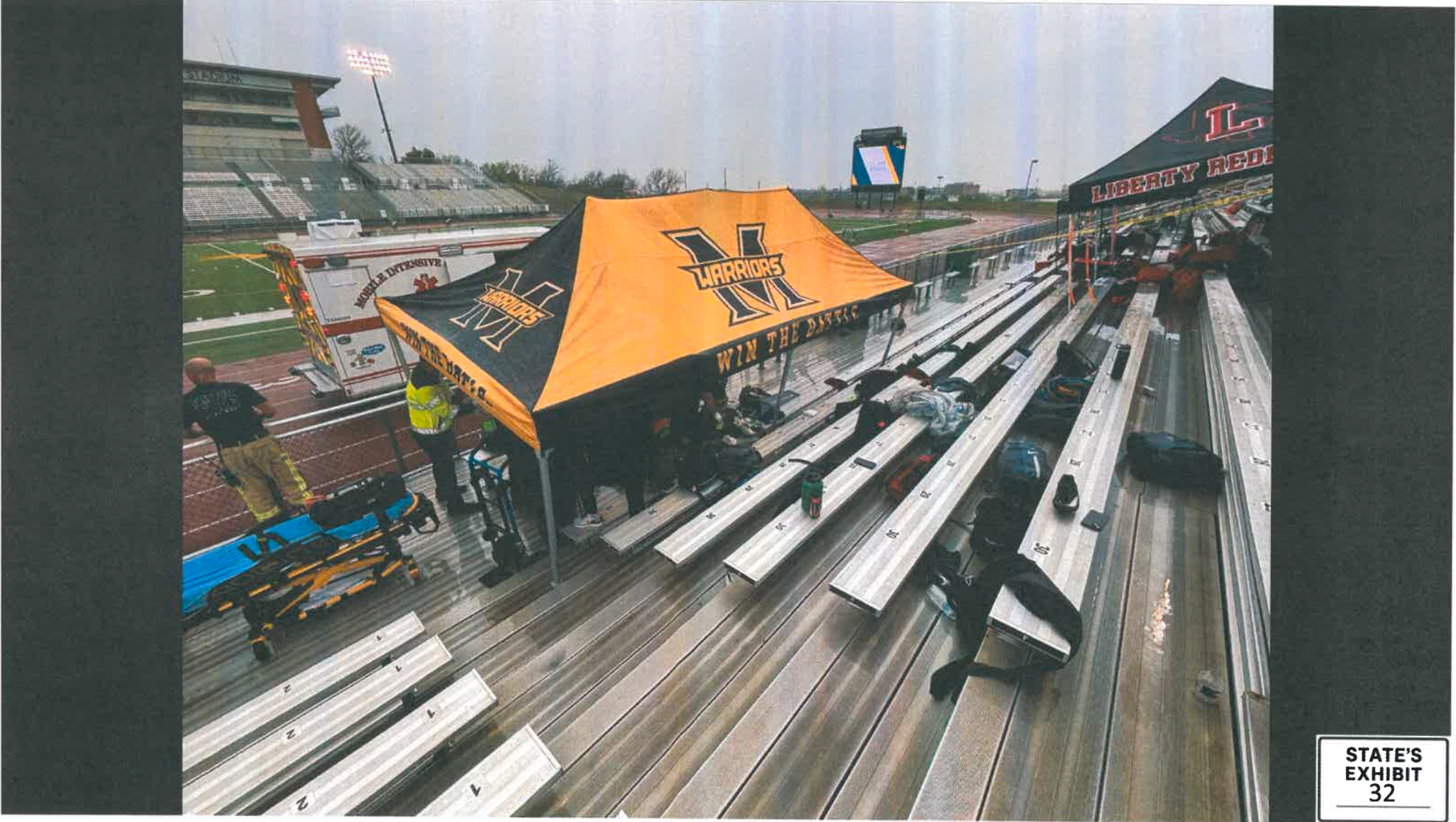A wider view of team tents and emergency responders in the stadium bleachers